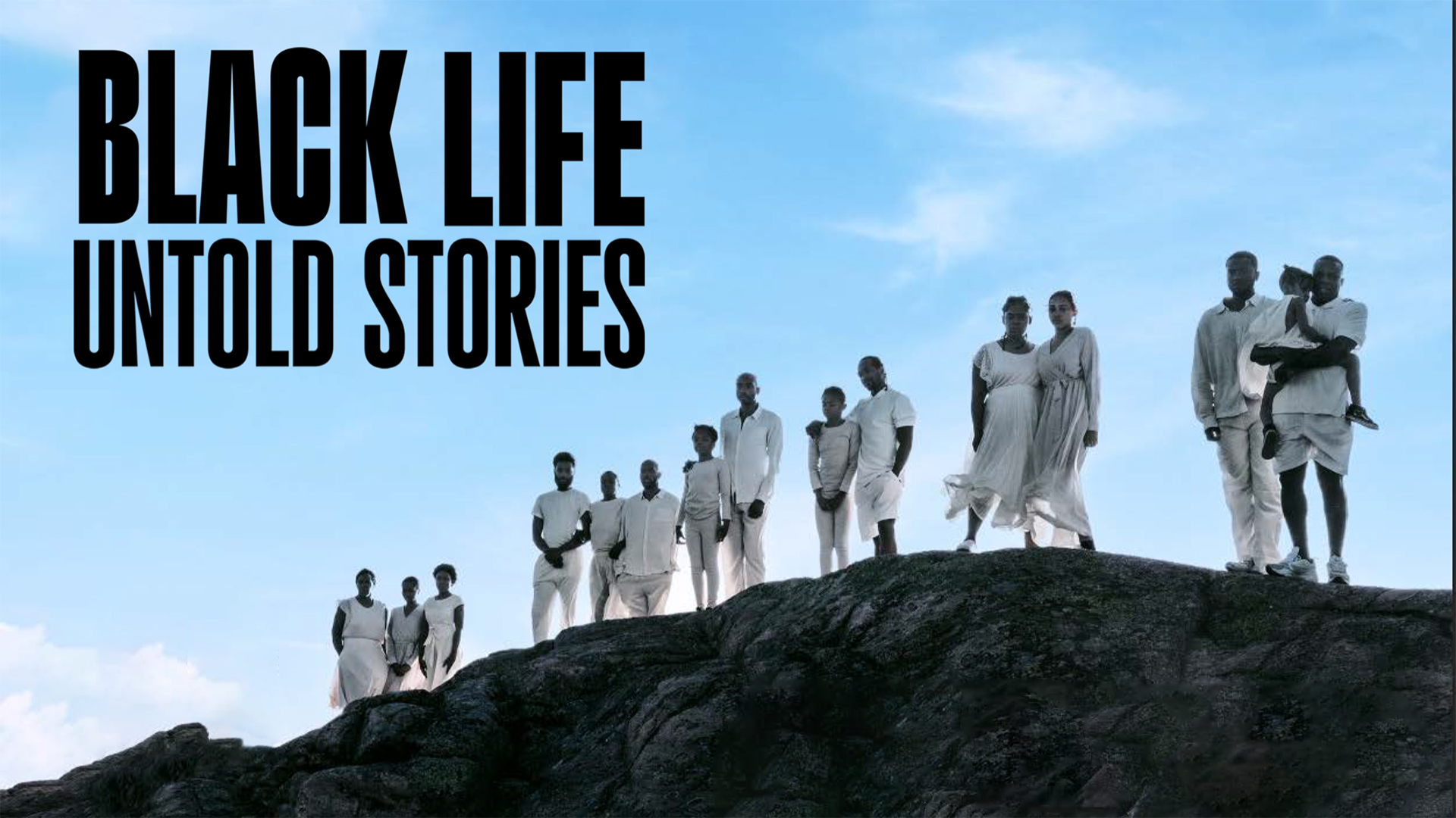 Black Life Untold Stories on-screen text. 15 Black people dressed in white stand on a rocky hill with the blue sky behind them/